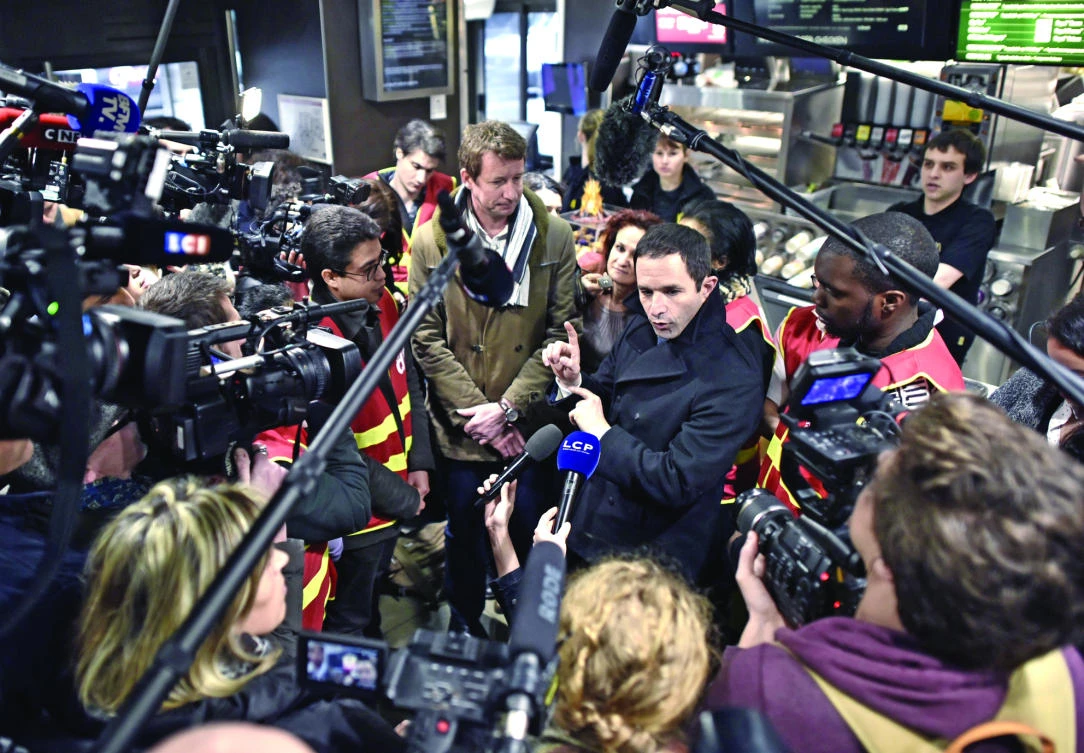 French presidential election candidate for the left-wing French Socialist (PS) party Benoit Hamon, center right, speaks in front of journalists next to former presidential candidate for the Green Party Europe-Ecologie-Les Verts (EELV) Yannick Jadot, center left, as they meet unionists of the General Confederation of Labour (CGT) at a fast-food in Paris on Monday. (AP)