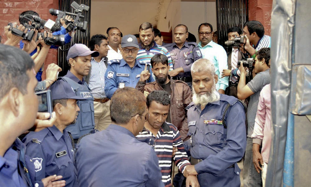 Bangladeshi policemen escort defendants, center, belonging to the militant group, Jumatul Mujahedeen Bangladesh, as they are brought to a court in Rangpur, Bangladesh, on Tuesday. (AP Photo)