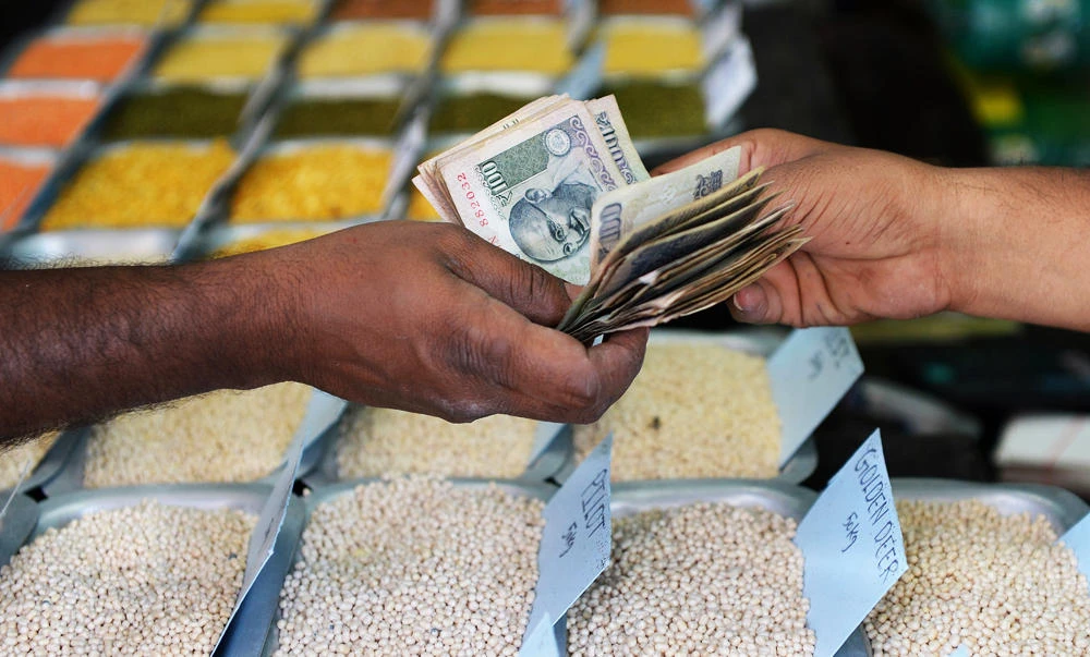 An Indian customer hands over cash to a food grain merchant at a wholesale trading shop in Bangalore on Tuesday. (AFP)