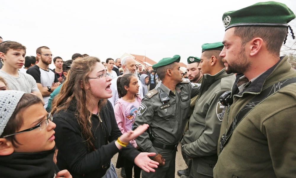 Israeli youths supporters of settlements argue with Israeli border guards in the settlement of Ofra in the occupied West Bank, during an operation by Israeli police to evict settlers' houses, on Tuesday. (AFP)
