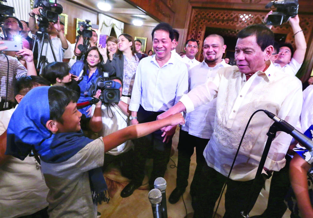 President Rodrigo Duterte, right, gestures with released Filipino hostage Rexon Romoc, left, 8-year-old boy kidnapped by the Abu Sayyaf in Payao, Zamboanga Sibugay on Aug. 5, 2016, as he is shown to reporters at the Malacanang palace in Manila Tuesday. (AP)