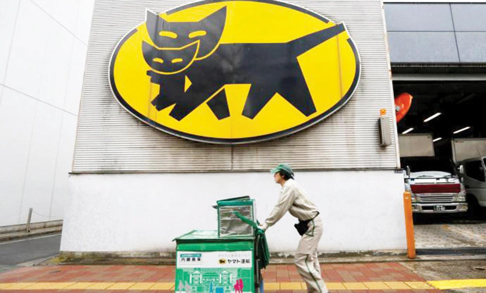 A deliverer of Yamato Transport Co. is seen under the company's logo at a business district in Tokyo, in this file photo. (Reuters)