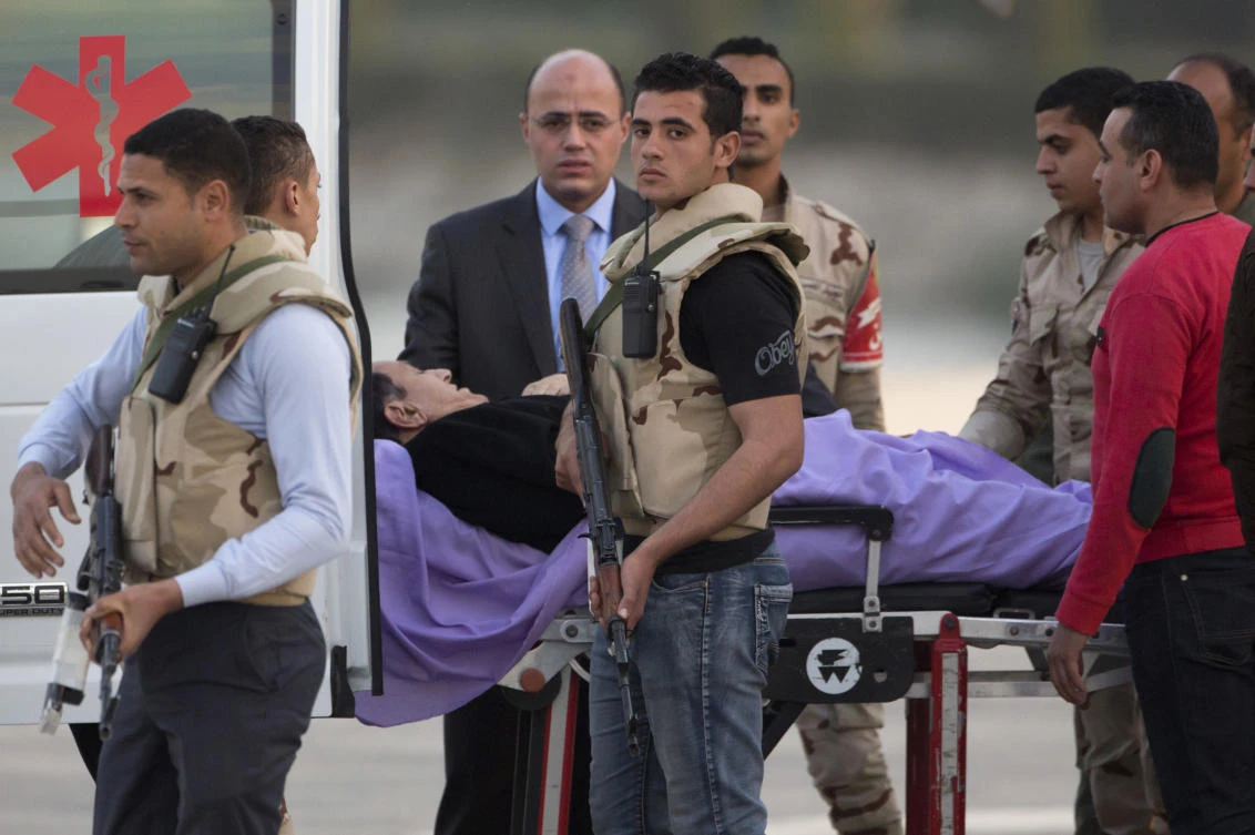 Ousted former Egyptian President Hosni Mubarak is escorted by medical and security personnel into an ambulance at Maadi Military Hospital. (AP)