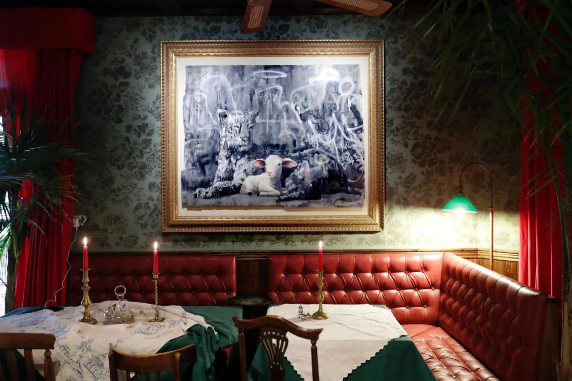 A Banksy installation hangs above the booths in the lobby at street artist Banksy's newly opened Walled Off hotel in the Israeli occupied West Bank town of Bethlehem, on March 3, 2017. Secretive British street artist Banksy opened a hotel next to Israel’s controversial separation wall in Bethlehem on Friday, his latest artwork in the Palestinian territories. / AFP / THOMAS COEX