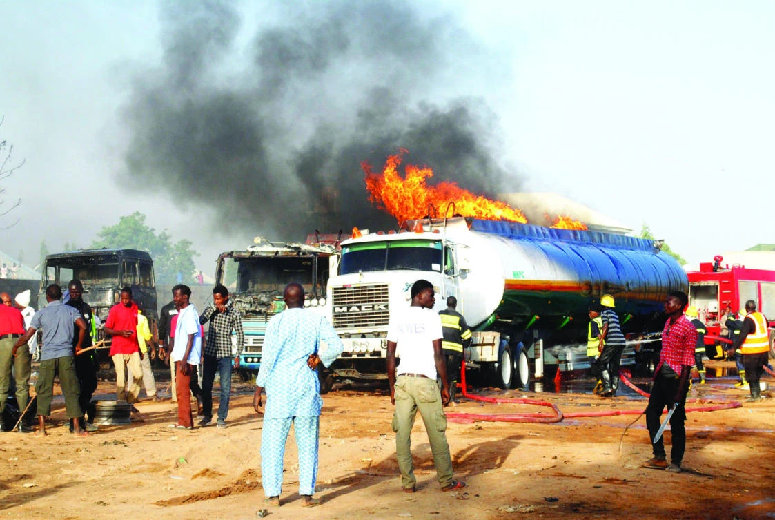 People stand near a petrol tanker on fire following a suicide attack in Maiduguri on Friday. (AFP)