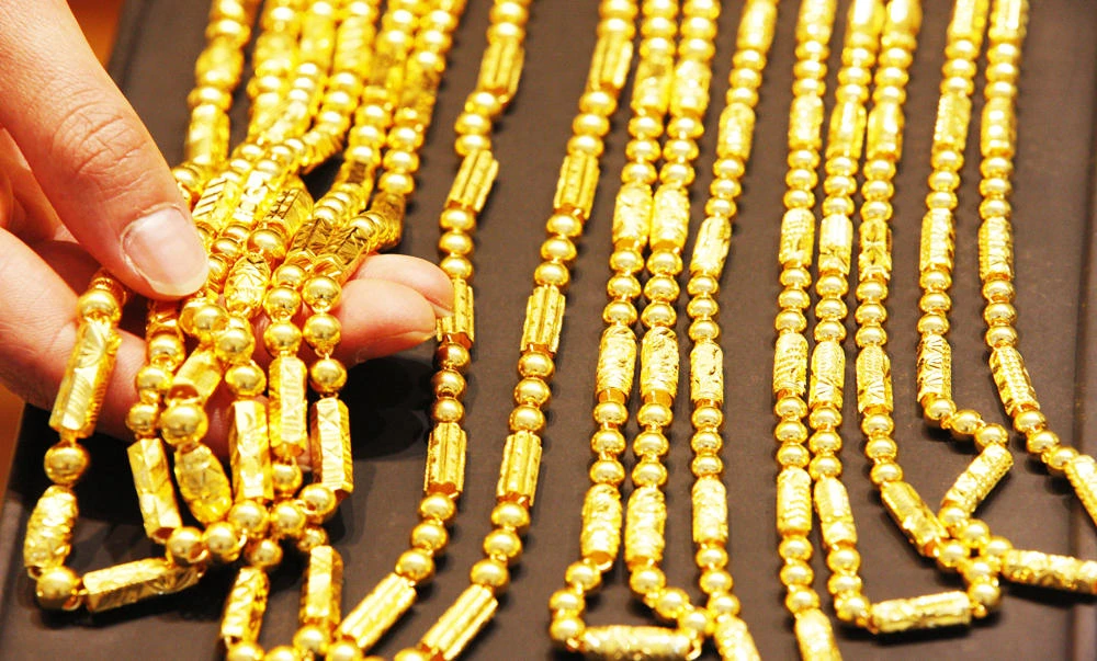 A sales girl arranges gold necklaces in a shop in Huaibei, central China's Anhui province, in this April 16, 2013 file photo. (AFP)