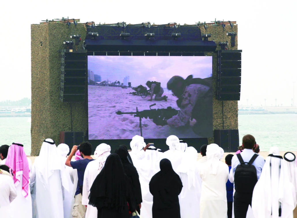 People watch a military drill on a large screen in Abu Dhabi. (AP)