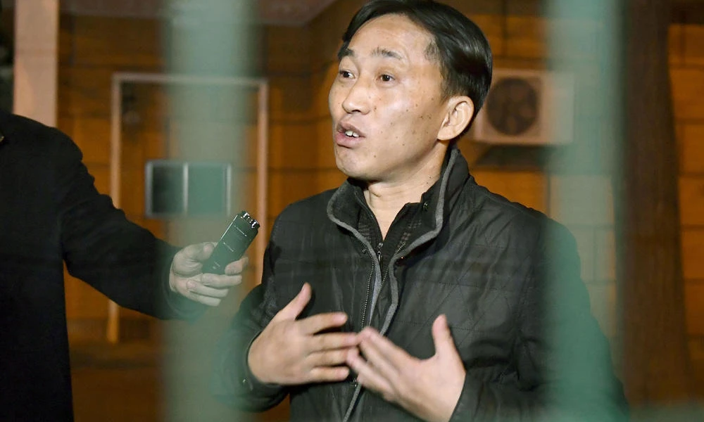 North Korean Ri Jong Chol speaks to reporters from behind a fence at the North Korean Embassy in Beijing early Saturday, a day after he was deported by Malaysian authoritie. (Naohiko Hatta/Kyodo News via AP)