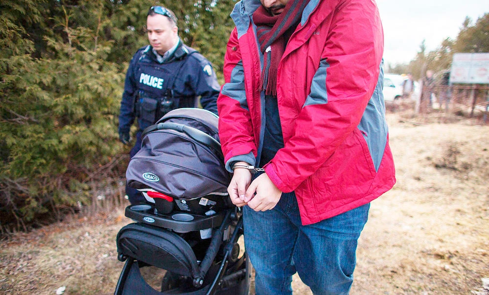A man is led away in handcuffs by the RCMP after he his wife and baby illegally crossed the Canada-US border near Hemmingford, Quebec, in this February 27, 2017 photo. (AFP)