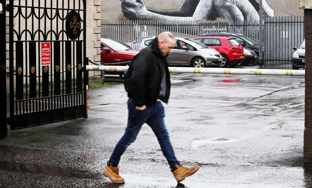 A man walks past an artwork by French street artist MTO entitled "The Son of Protagoras" depicting a squatting child holding a dove killed by two arrows, one representing Catholicism and the other Protestantism, in Belfast, Northern Ireland, in this February 28, 2017 photo. (AFP)