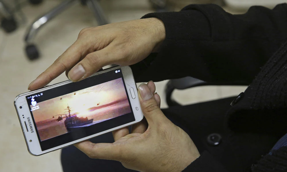 Farhad Azima, Iranian director and screenwriter of the animated film, "Battle of the Persian Gulf II," shows a clip from the movie on his cell phone during an interview with The Associated Press, at his office in Tehran on Feb. 26, 2017. (AP Photo/Vahid Salemi)