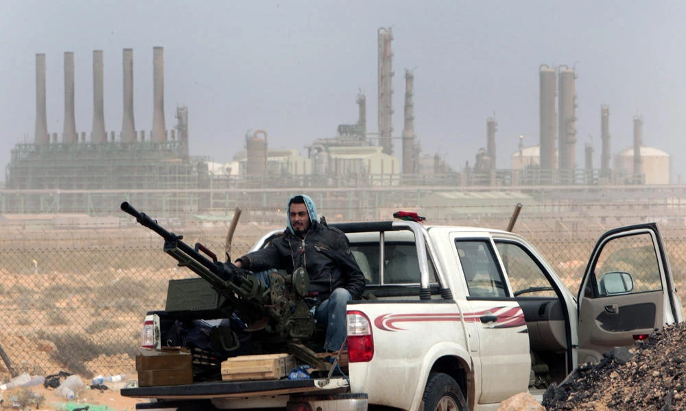 In this March 5, 2011 file photo, an anti-government rebel sits with an anti-aircraft weapon in front an oil refinery in Ras Lanouf, eastern Libya. Libyan armed forces based in the east have launched more airstrikes against militias that seized oil terminals a day earlier, saying forces from the country's rival west were declaring war against them. (AP Photo/Hussein Malla, File)