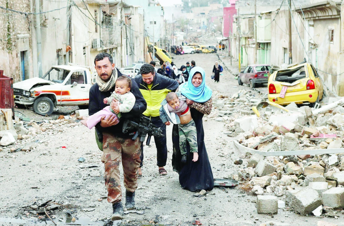 An Iraqi special forces soldier helps a family carry their children to cross from a Daesh-controlled part of Mosul to an Iraqi forces-held area on Saturday. (Reuters)