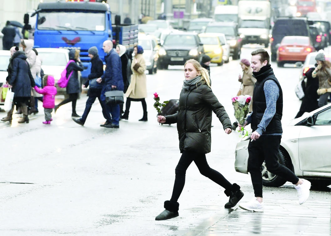 Young persons carrying red roses cross a road in Moscow on Monday, two days before International Women’s Day, also known as the March 8 holiday. (AFP)