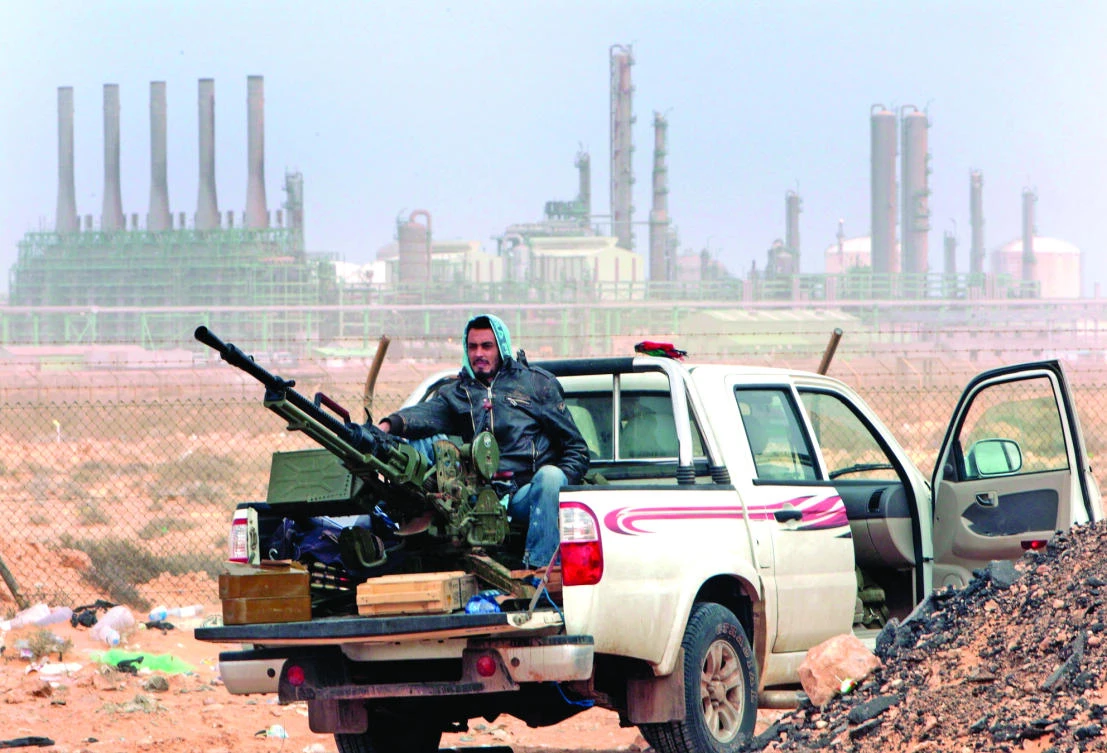 An anti-government fighter sits with an anti-aircraft weapon in front an oil refinery in Ras Lanouf, eastern Libya, in this March 2011 photo. (AP)
