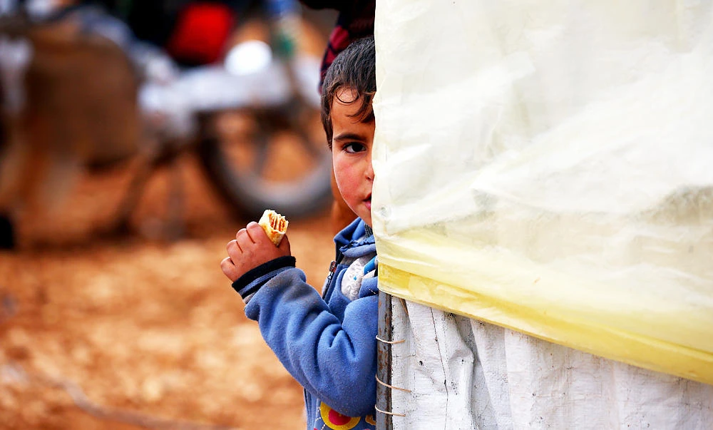 A displaced Syrian child, who fled their hometowns due to clashes between regime forces and the Islamic State (IS) group, eats outside a tent in Kharufiyah, 18 kilometres south of Manbij, in this March 4, 2017 photo. (AFP)