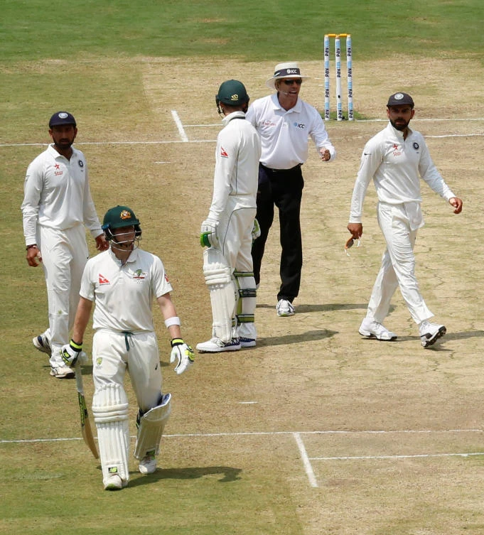 India's captain Virat Kohli, right, speaks to the umpire as Australia's captain Steven Smith, second left, walks off the ground after being dismissed at the M Chinnaswamy Stadium, Bengaluru, on Tuesday. (Reuters)