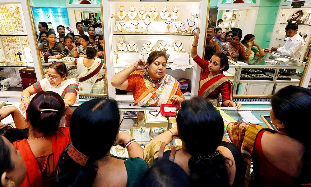 A saleswoman displays a gold earring to customers at a jewellery showroom during Dhanteras, a Hindu festival associated with Lakshmi, the goddess of wealth, in Kolkata, India, in this October 28, 2016 file photo. (REUTERS)
