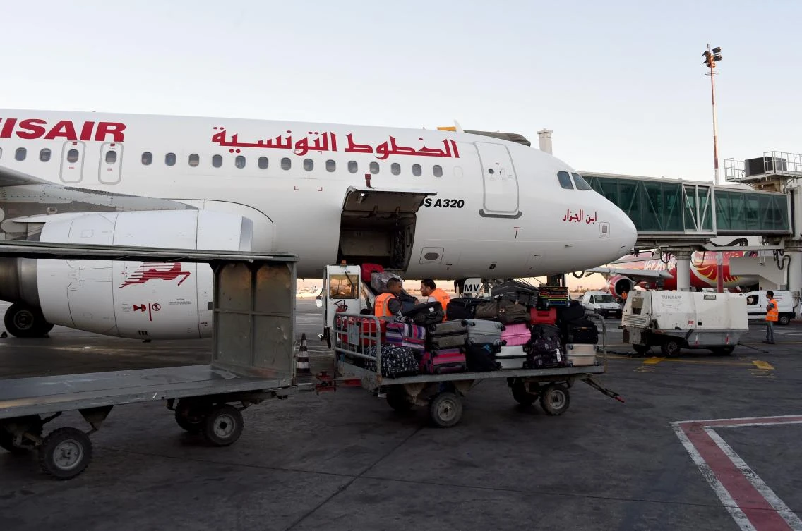 Tunis-Carthage International Airport shows a laborer transporting luggage next to a Tunisair plane. (AFP)