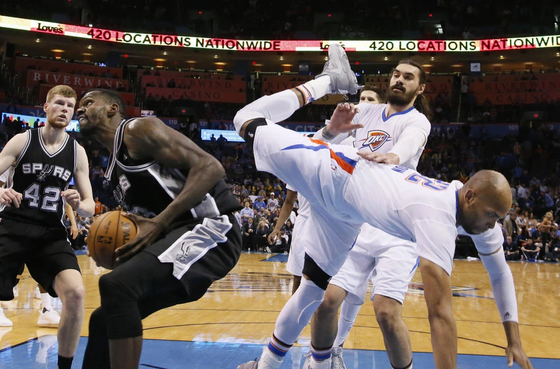 Oklahoma City Thunder forward Taj Gibson, right, topples over San Antonio Spurs center Dewayne Dedmon, left, during the fourth quarter of an NBA basketball game in Oklahoma City on Thursday. (AP)