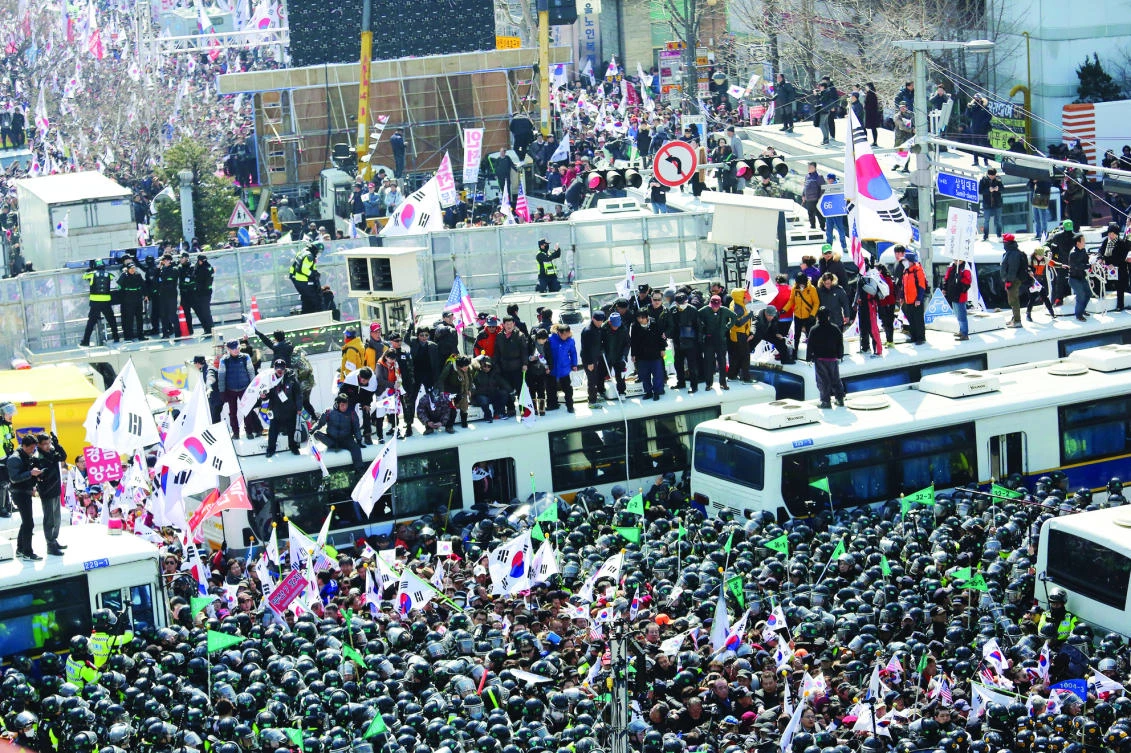 Supporters of South Korean President Park Geun-hye are blocked by police buses as they march toward the Constitutional Court after a rally opposing her impeachment in Seoul on Friday. (AP)