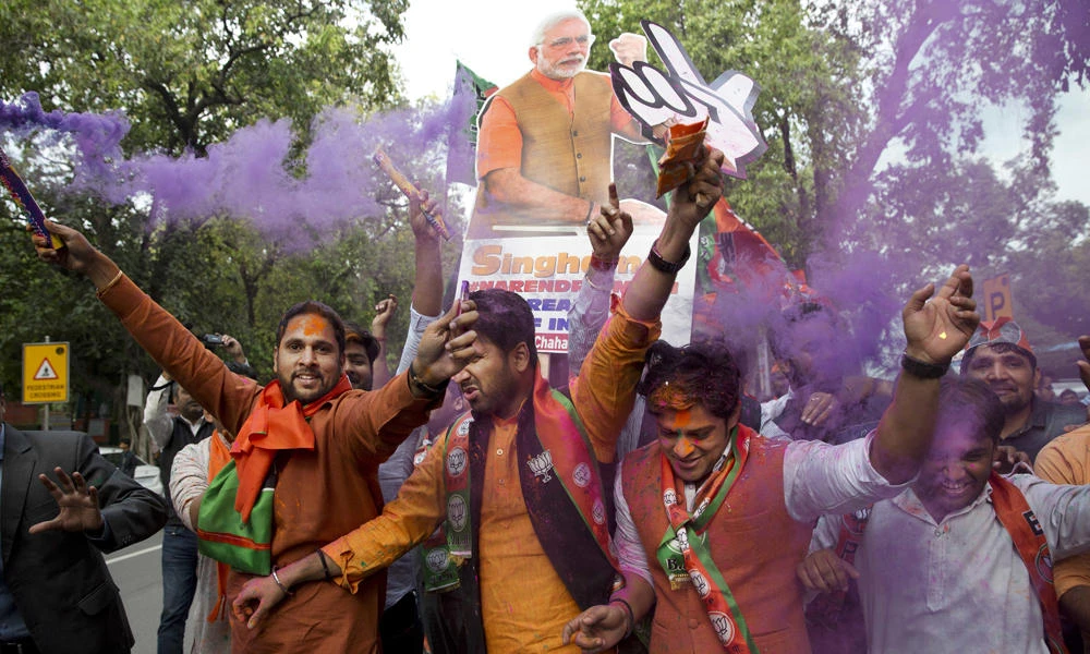 Bharatiya Janata Party (BJP) supporters celebrate in New Delhi on Saturday as their party leads in state elections in Uttarakhand and Uttar Pradesh states. (AP Photo/Tsering Topgyal)