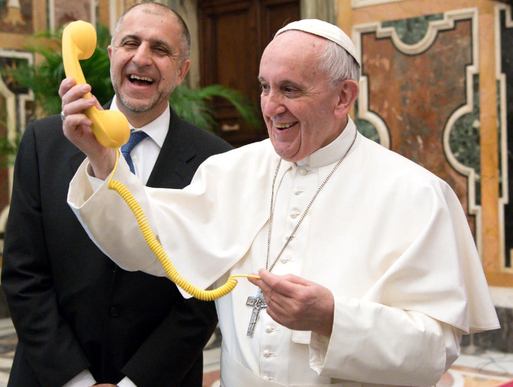 Pope Francis shares a light moment with "Telefono Amico" support hotline president Dario Briccola during an audience at the Vatican Saturday. The pope is considering a visit to Egypt in May. (L'Osservatore Romano/Pool Photo via AP)