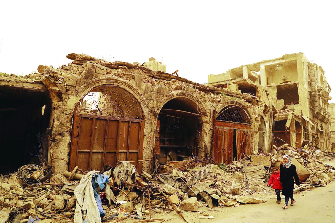 Syrian girls walk past destroyed buildings in Bab Al-Nasr neighborhood, Aleppo. (AFP)