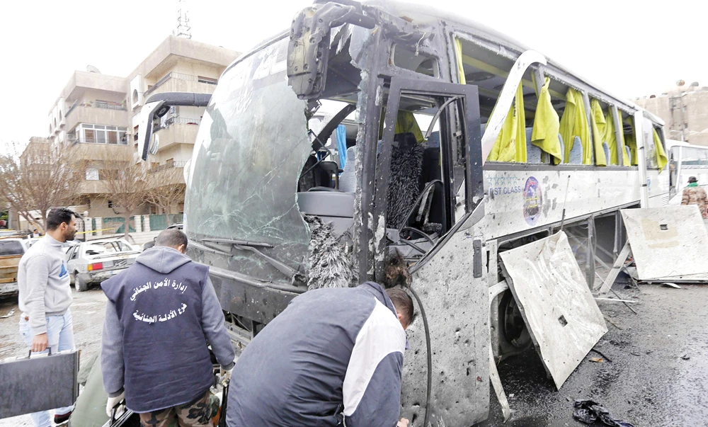 Forensic experts examine a damaged bus at the scene of a bombing in Damascus on Saturday. (AFP)