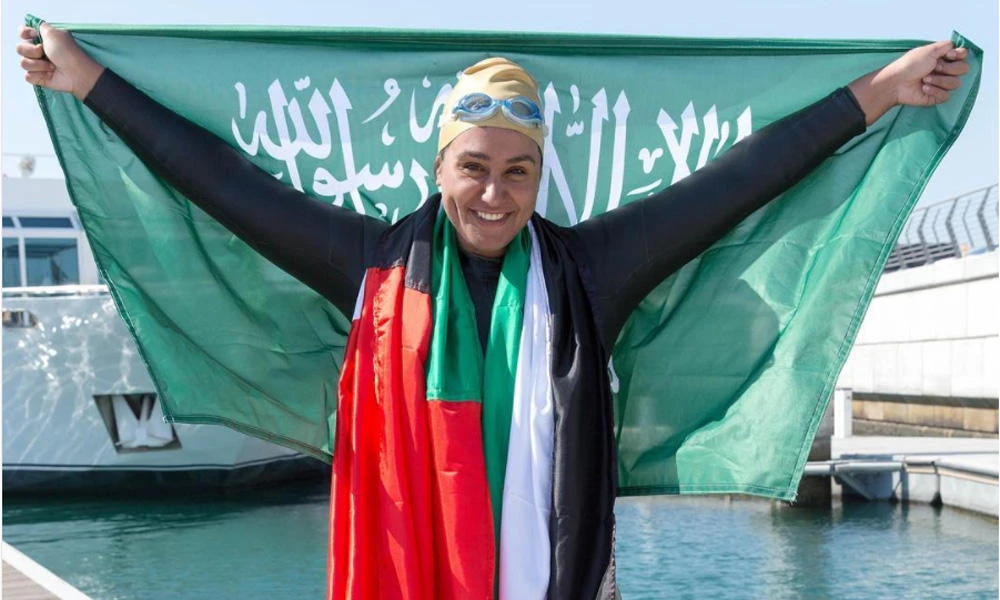 Dr. Mariam Saleh Binladen raises the Saudi flag as she celebrates after completing a 24-kilometer swim across the Dubai Creek and Dubai Canal on March 10, 2017. (Courtesy: Mariam S. Binladen’s Instagram account)