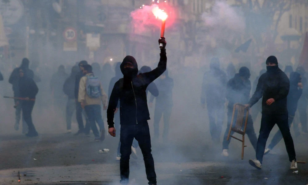 A protester holds a lit flare during clashes with riot police during a demonstration against the visit of the leader of the Northern League party Matteo Salvini, in Naples, Italy, on Saturday. (Ciro Fusco/ANSA via AP)