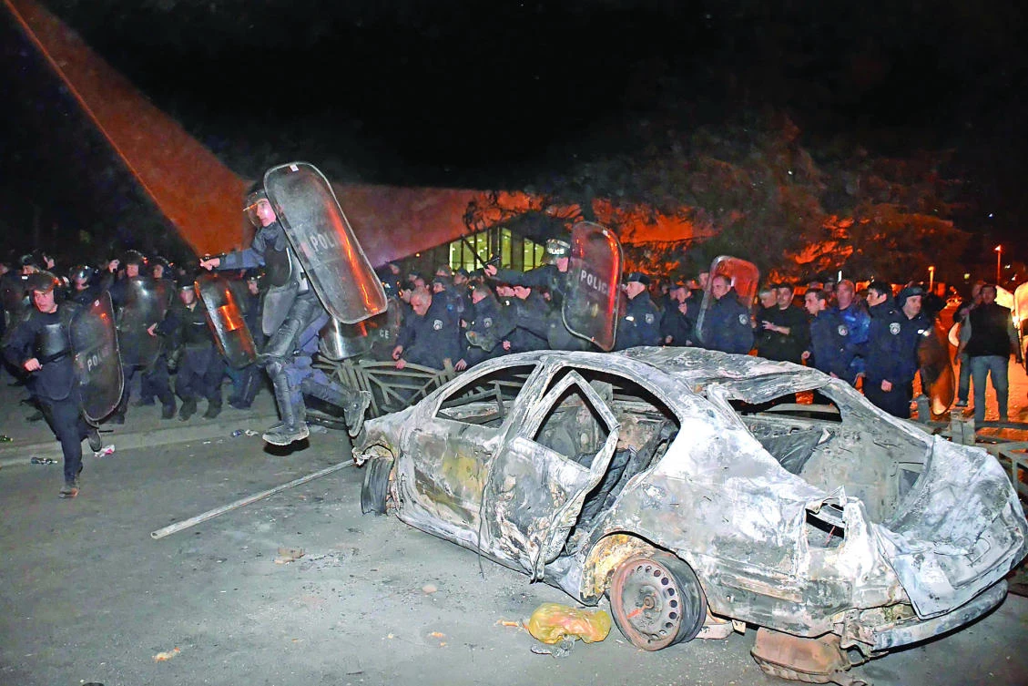 A Georgian riot police officer jumps over a burned car early on Sunday in Georgia’s Black Sea port of Batumi during clashes between police and stone-throwing rioters reportedly following a spontaneous protest by local residents against police officers arresting several men who refused to accept a parking fine. (AFP)
