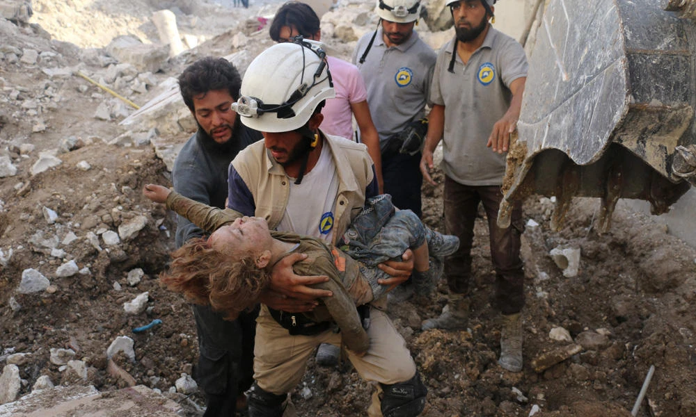In this October 4, 2016 photo, a Syrian civil defense volunteer, known as the White Helmets, carries the body of a child pulled from the rubble following an air strike on the rebel-held neighborhood of Karm Homad in the northern city of Aleppo, Syria. UNICEF on Monday said at least 652 children were killed in Syria in 2016, making it the worst year yet for the country’s rising generation. (AFP file photo)