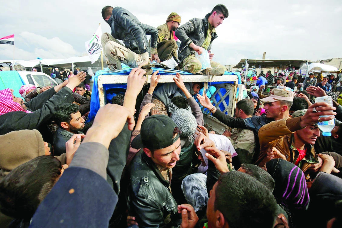 Displaced Iraqis receive aid rations at the Hammam Al-Alil camp, south of Mosul. (AFP)