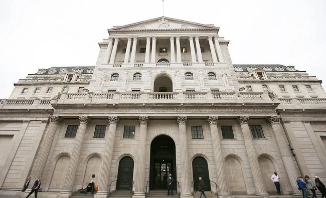 Pedestrians walk past the main entrance to the The Bank of England in the City of London on Friday. (AFP)