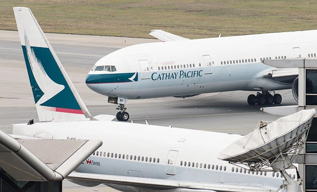 A Cathay Pacific Boeing 777 passenger aircraft (top) taxis past a stationary plane on the tarmac at the international airport in Hong Kong on Wednesday. (AFP)