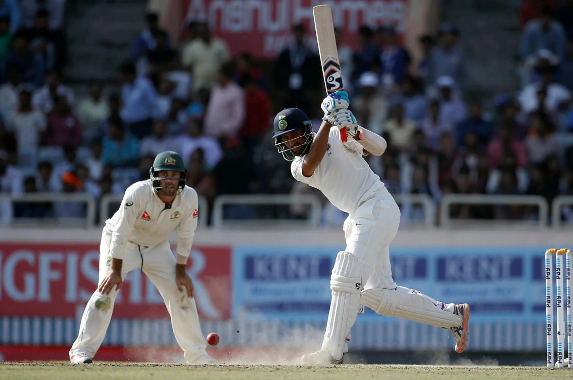 India's Cheteshwar Pujara plays a shot as Australia's Glenn Maxwell watches at the Jharkhand State Cricket Association Stadium, Ranchi, on Saturday. (Reuters)