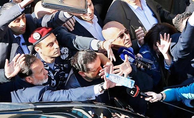 Bodyguards protect Lebanese PM Saad Hariri, center, from a water bottle thrown by demonstrators in downtown Beirut, Lebanon, on Sunday. (AP)