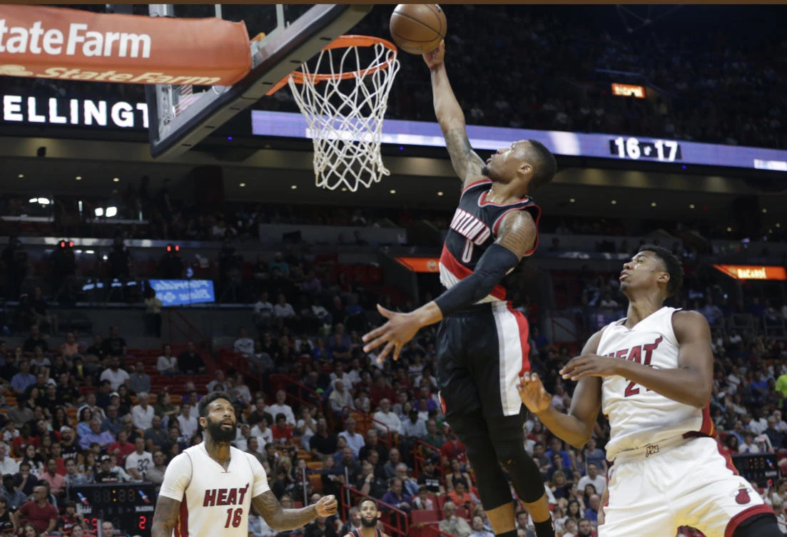 Portland Trail Blazers' Damian Lillard (0) dunks over Miami Heat's James Johnson (16) and Hassan Whiteside (21) during the first half of an NBA basketball game in Miami on Sunday night. (AP)