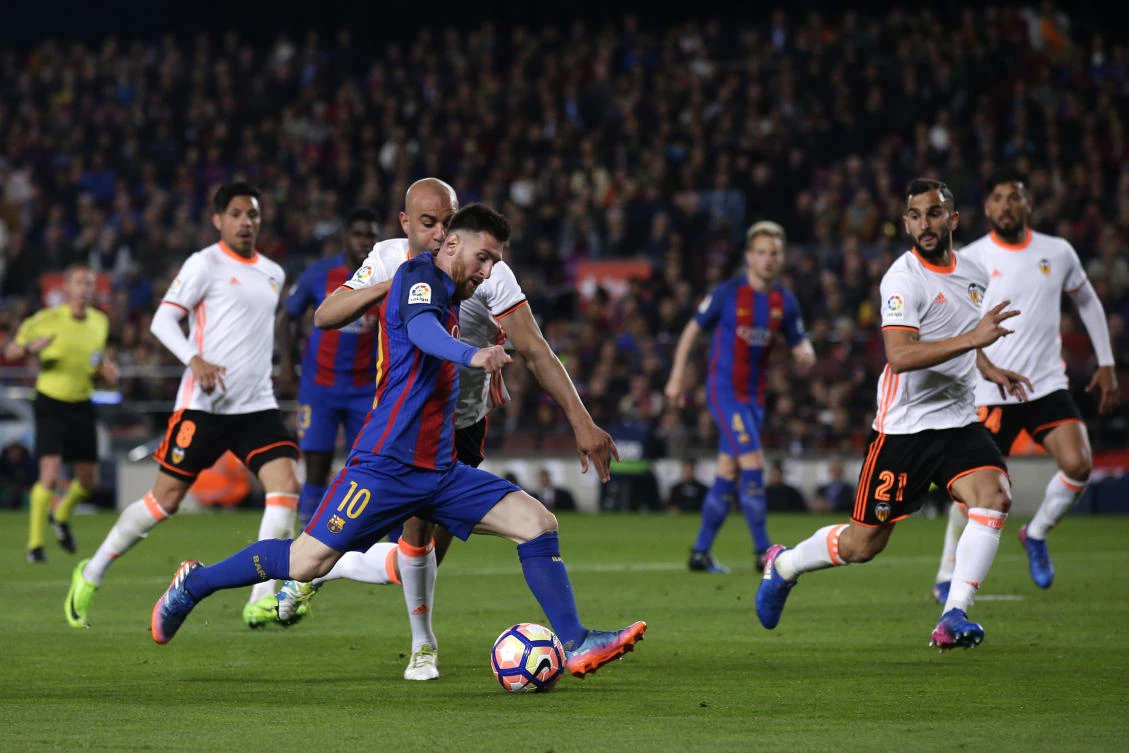 Barcelona's Lionel Messi, center, scores under pressure of Valencia's Aymen Abdennour, center back, during the Spanish La Liga soccer match at the Camp Nou stadium in Barcelona on Sunday. (AP)