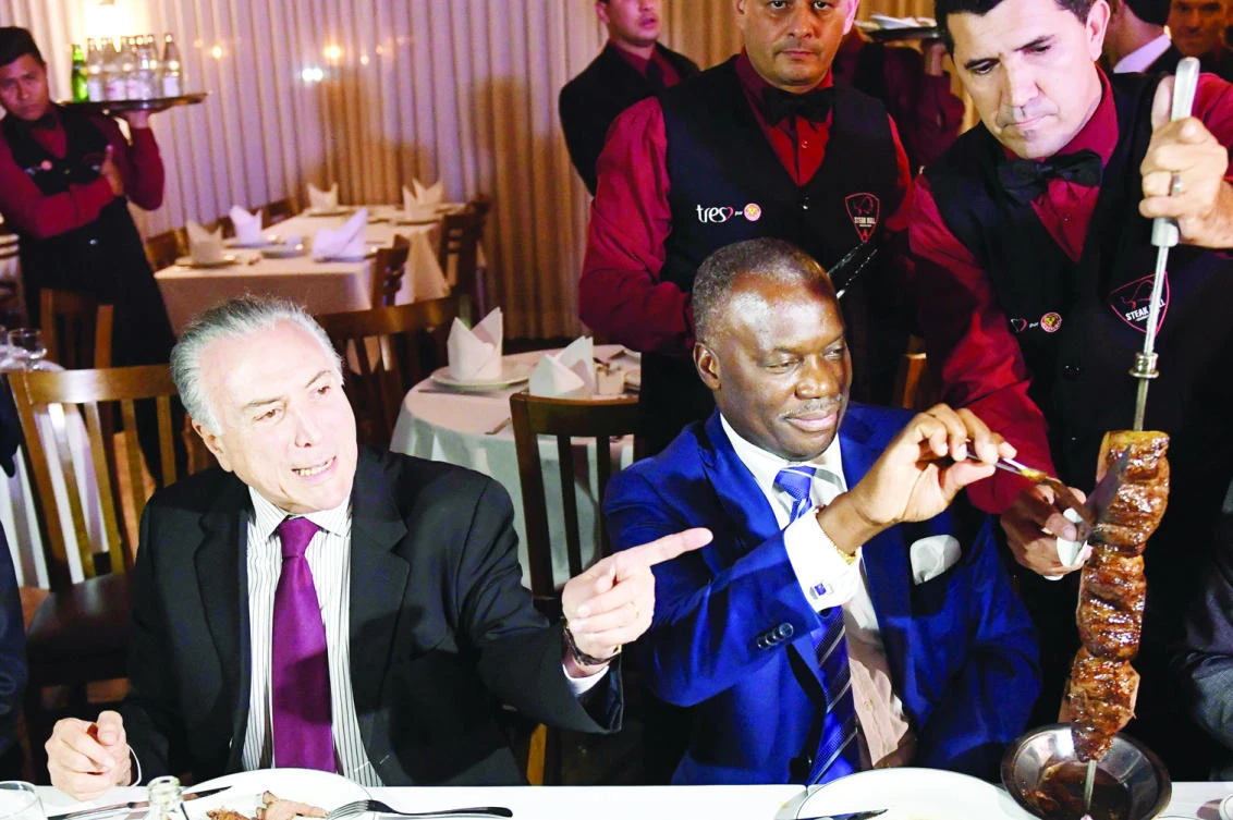 Brazilian President Michel Temer and Angola’s Ambassador Nelson Manuel Cosme eat barbecue in a steak house in Brasilia after a meeting with ambassadors from countries that import Brazilian meat, on Sunday. (AFP)