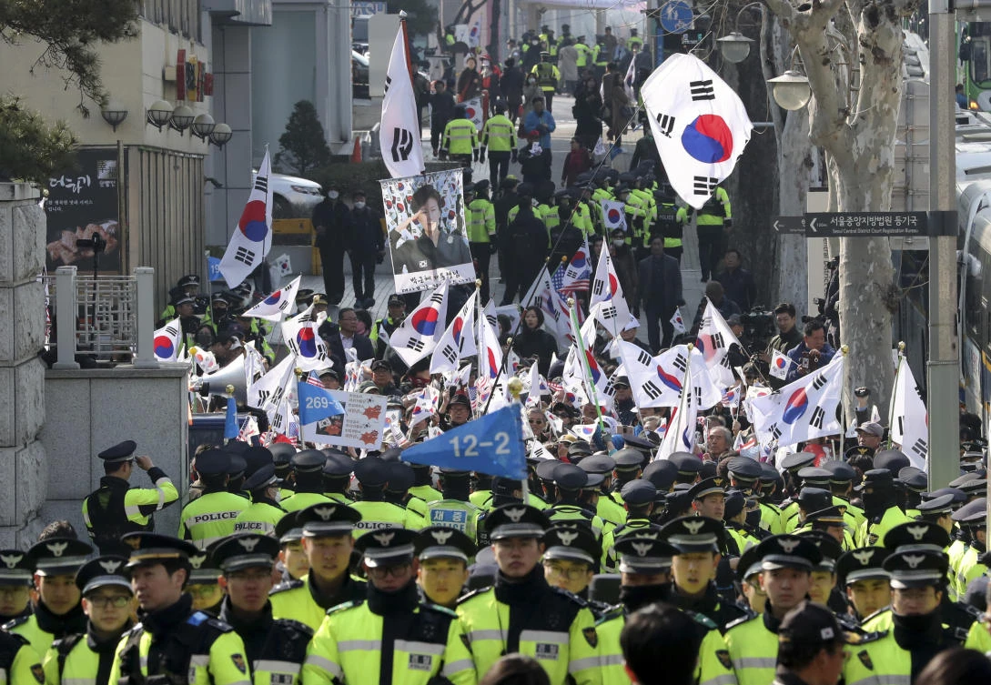 Supporters of South Korean ousted President Park Geun-hye wave national flags and picture of Park outside of a prosecutors’ office in Seoul, South Korea. (AP)