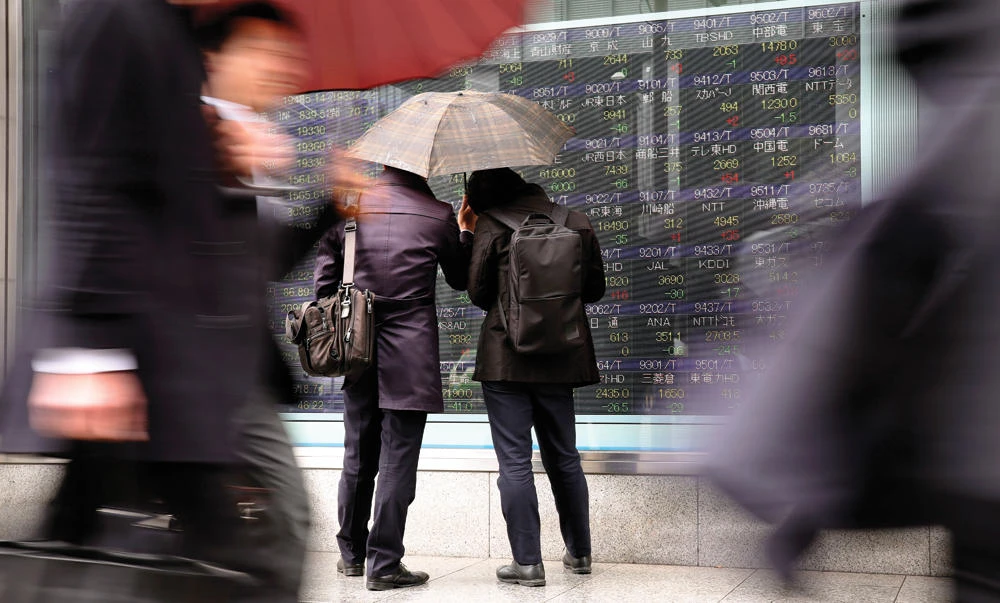 Men look at an electronic stock indicator of a securities firm in Tokyo, on Tuesday. Asian shares were mixed in lackluster trading on Tuesday, as markets searched for a dominant theme, weighing currency fluctuations, signs of growing protectionism and other uncertainties. (AP)