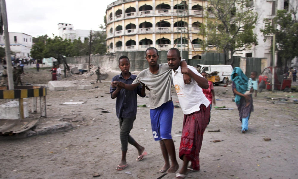 An injured man is assisted after a suicide car bomb attack that targeted a check point in Mogadishu, Somalia, on Tuesday. (AP Photo/Farah Abdi Warsameh)