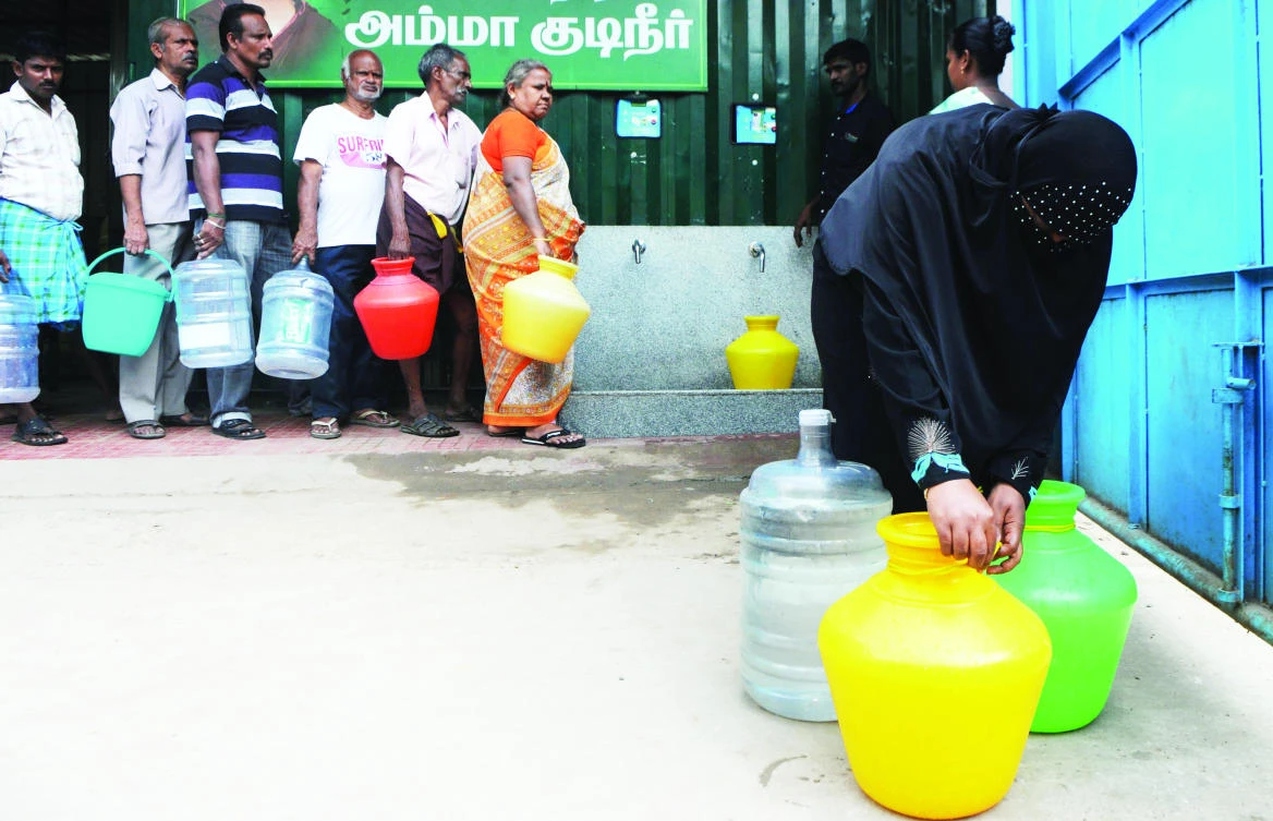 An Indian prepares to carry plastic containers full of drinking water after collection from a government distribution center in Chennai Wednesday. (AFP)