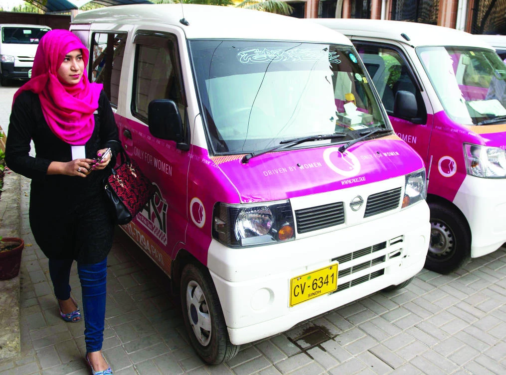 A driver with the women-only Paxi Pakistan taxi company walks past a Pink Taxi during its launch ceremony in Karachi on March 8. (AFP)