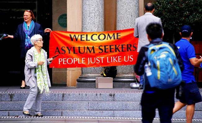 Pedestrians walk past refugee advocates as they hold a banner on the steps of the Customs House building in the central business district (CBD) of Sydney, Australia, in this March 8, 2017 photo. (REUTERS)
