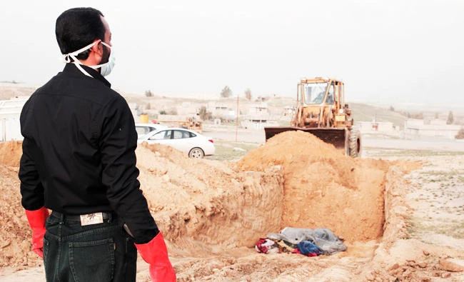 A man watches heavy equipment work at the burial site for bodies found in a mass grave containing some two dozen people, many of them children, in an area recently re-taken from Islamic State militants in Hamam al-Alil, Iraq, in this March 15, 2017 photo. (AP)