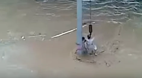 In this screen grab from a video published on YouTube, Pakistani national Farman Ali Khan is shown rescuing a man stranded on an electric pole at an underpass during the 2009 flood in Jeddah. Khan saved 14 lives but lost his own while trying to save the 15th person.