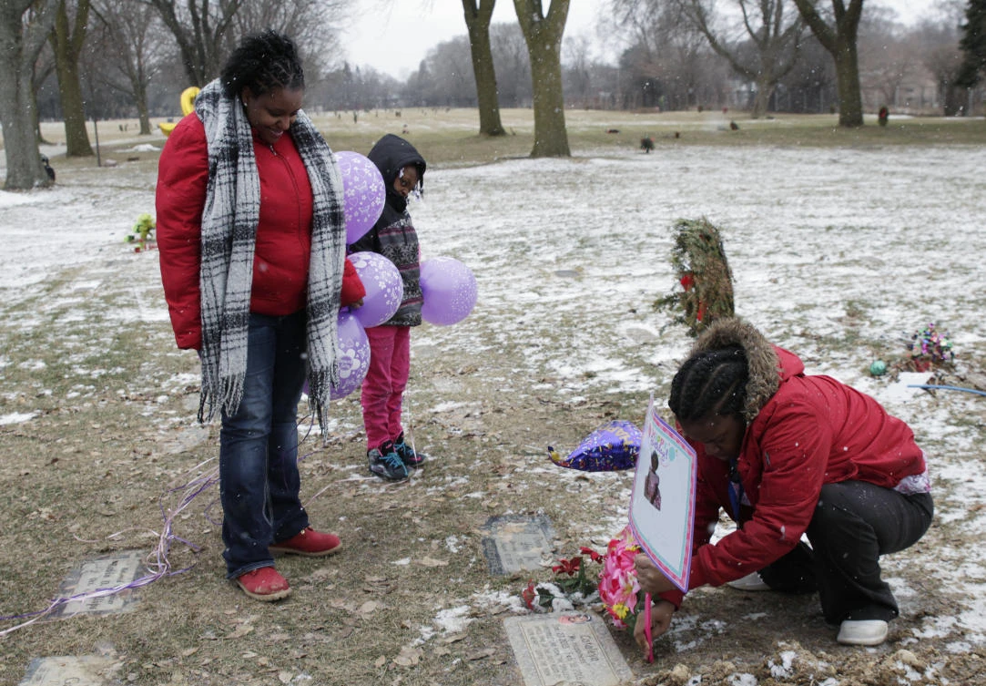 Helen Jackson, left, along with her daughter Raniah Ricks, center, and Brittany Blake visit the grave of Jackson's daughter Cataleya Tamekia-Damiah Wimberly who died aged one. (AP)